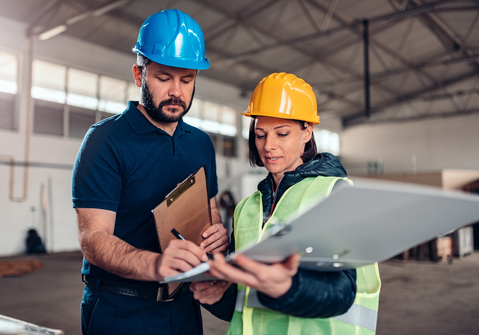 Factory worker signing document in industrial hall